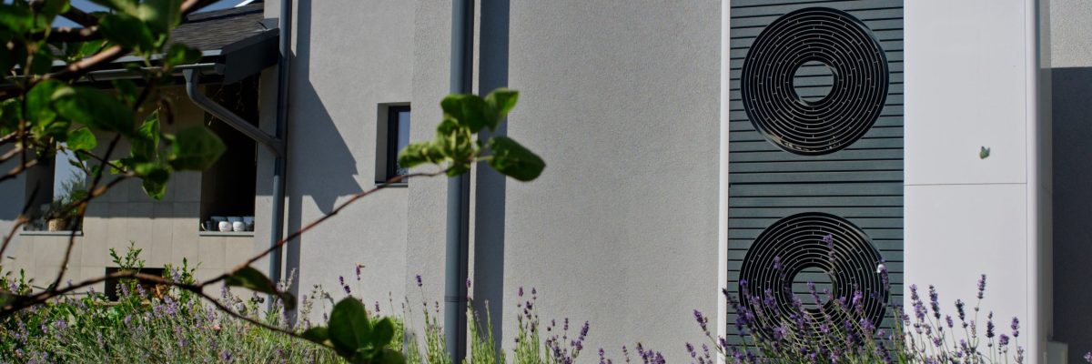 Montaż pompy ciepła Koluszki – jednostka zewnętrzna ustawiona przy elewacji nowoczesnego domu, otoczona roślinnością i lawendą.